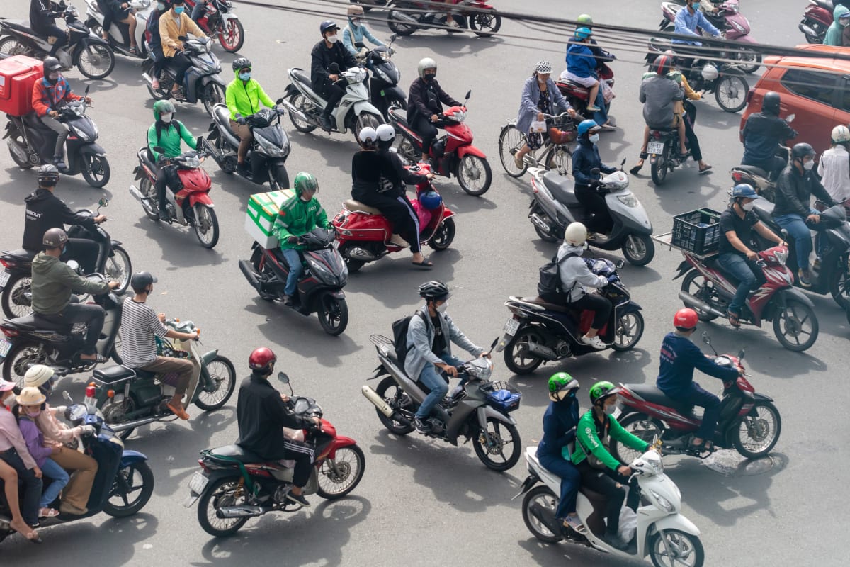Scooter traffic seen from above, riders weaving in every direction across the road — Paul Evan Green
