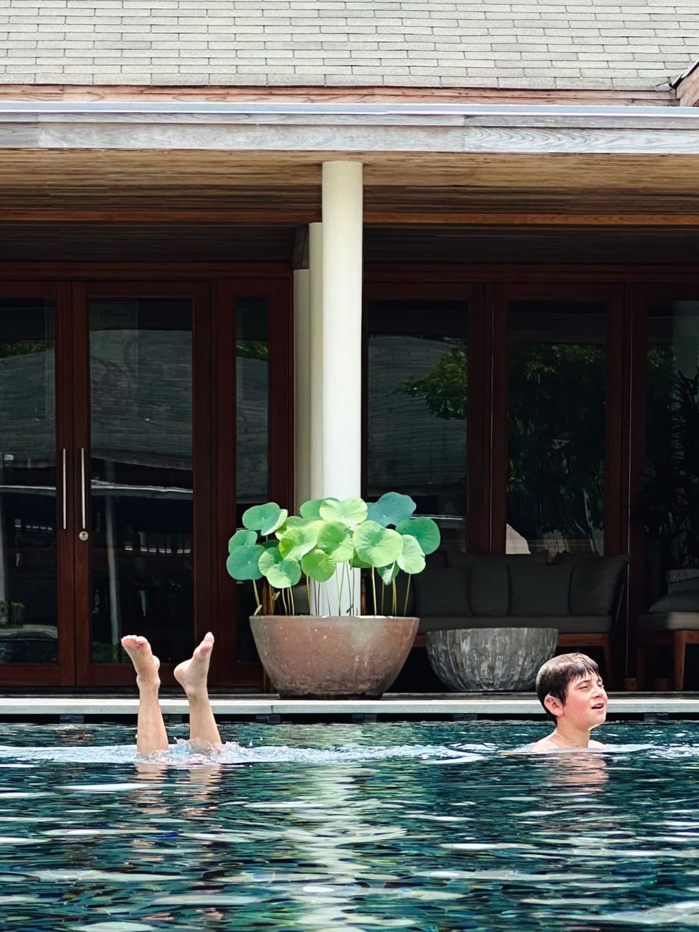 Child watches a synchronized swimmer's legs in a villa pool — Le Hoang Tuan