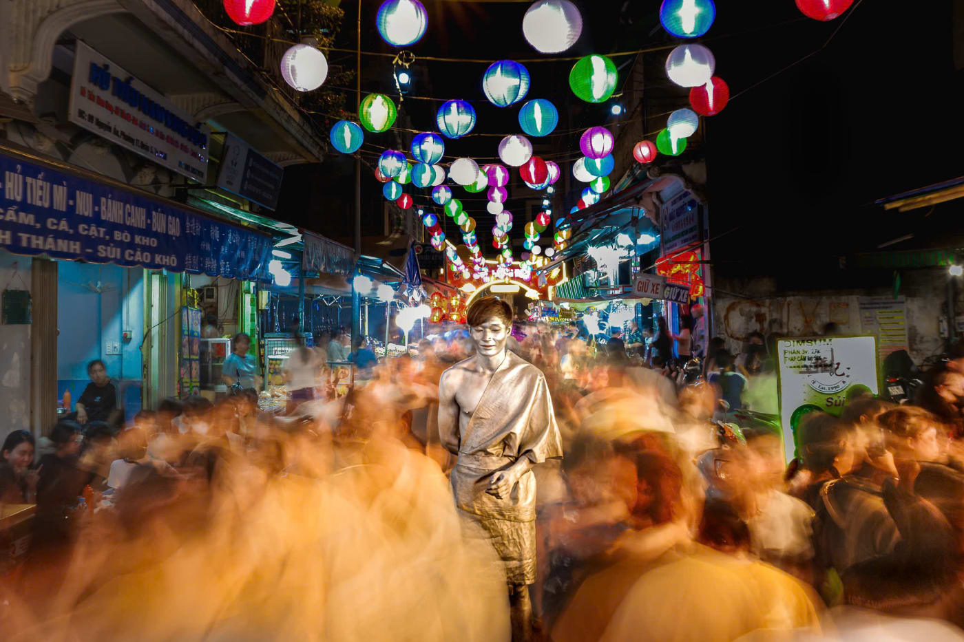 A still figure surrounded by motion-blurred crowds under Mid-Autumn lanterns on Luong Nhu Hoc Street — MatDat.Ng