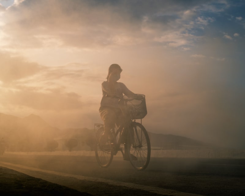 A cyclist riding through a cloud of golden dust at low sun, mountains faint behind