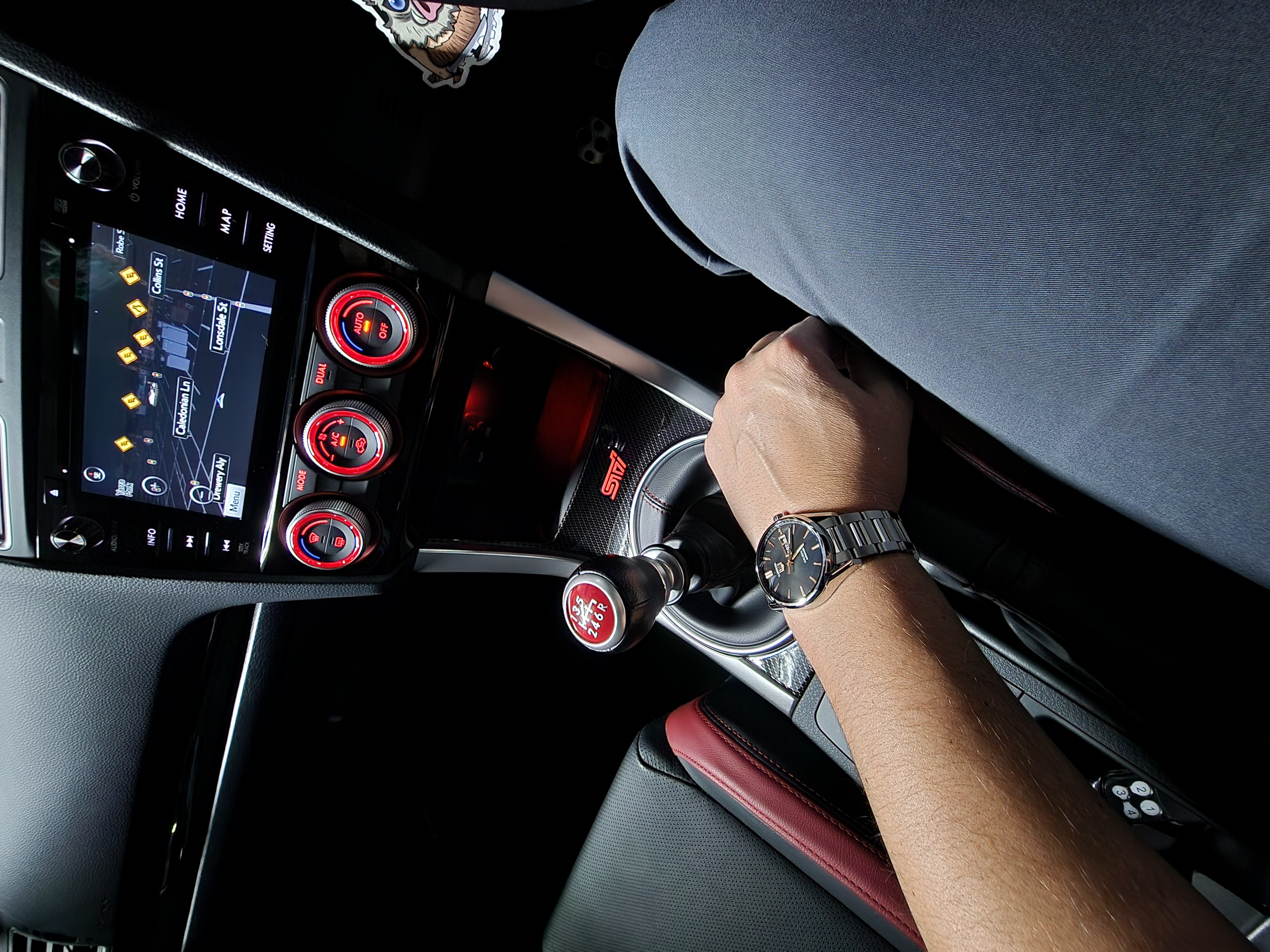 Hand on STI gear shifter, red interior, city navigation