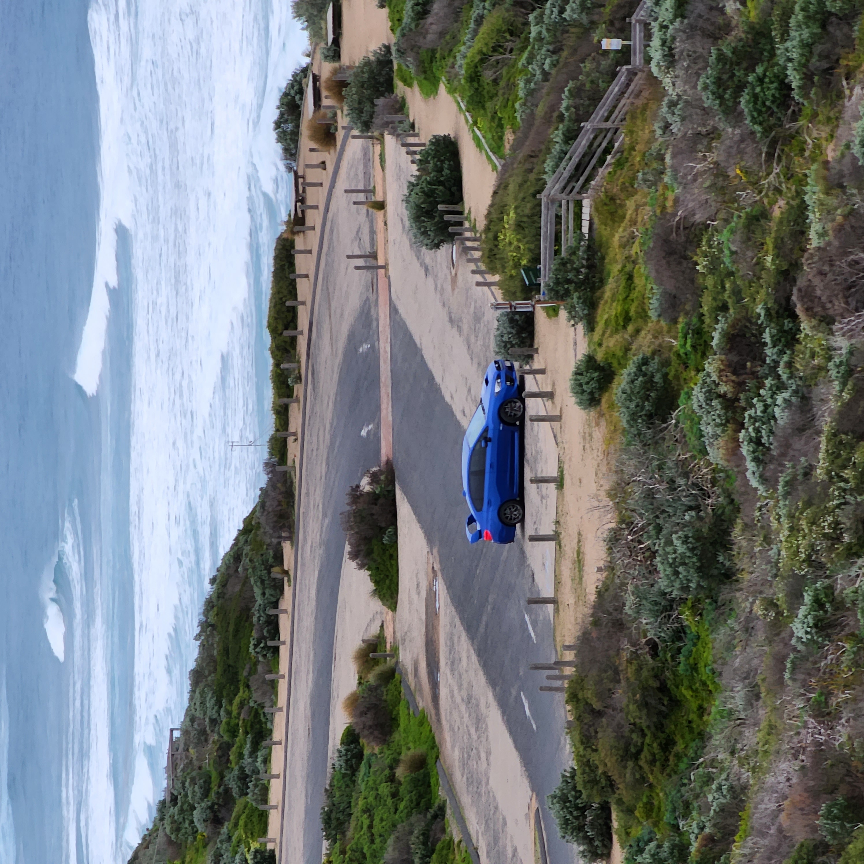 2016 Subaru WRX STI parked alone at coastal lookout, surf breaking behind
