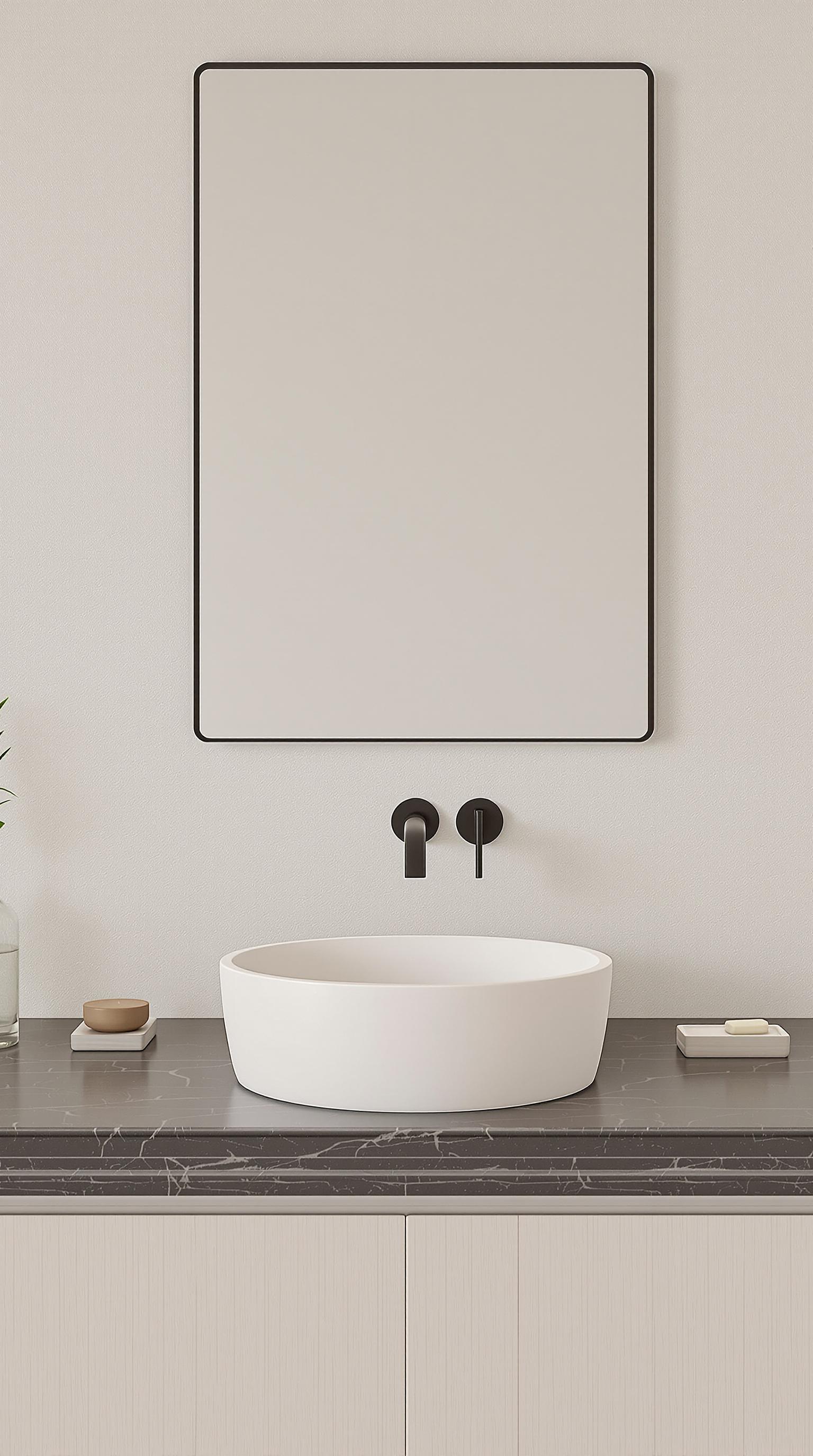 Create a design featuring a round, deep sink made of ceramic in a soft matte white finish, placed on a sleek, dark stone countertop. Replace the faucet with a modern, matte black pull-down faucet and use a large, elegant square mirror above the sink. Add a tall, clear glass vase with a single green leaf and a set of minimalist, muted-toned soap dishes beside the sink. The wall should have a textured, light-colored finish for a warm, inviting atmosphere.