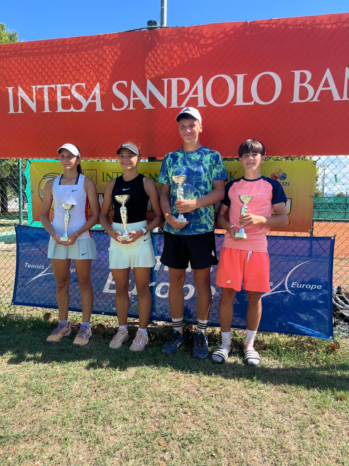 Štyria mladí hráči s pohármi na medzinárodnom turnaji Tennis Europe