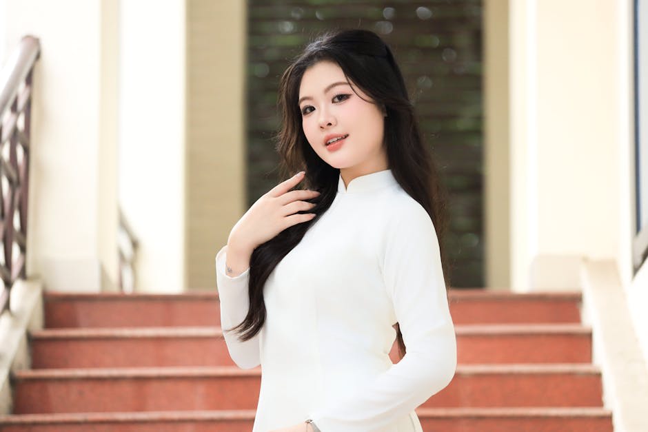 Thời trang nữ trẻ trung - Một người phụ nữ duyên dáng đứng trên cầu thang trong chiếc áo dài trắng, thể hiện văn hóa và 