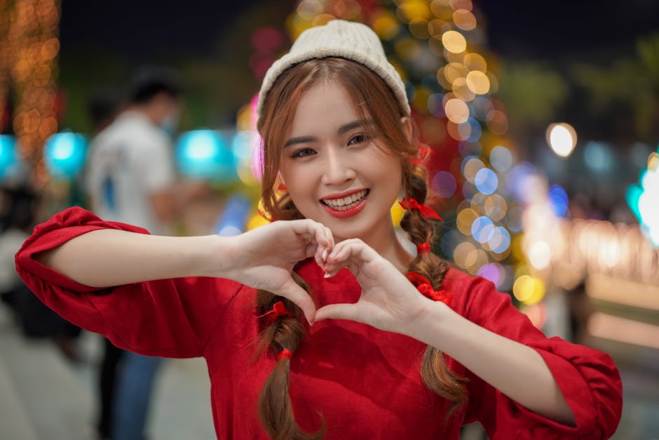 Thời trang nữ mùa đông - Một người phụ nữ vui vẻ trong trang phục lễ hội đang tạo hình trái tim bằng tay trong bối cảnh