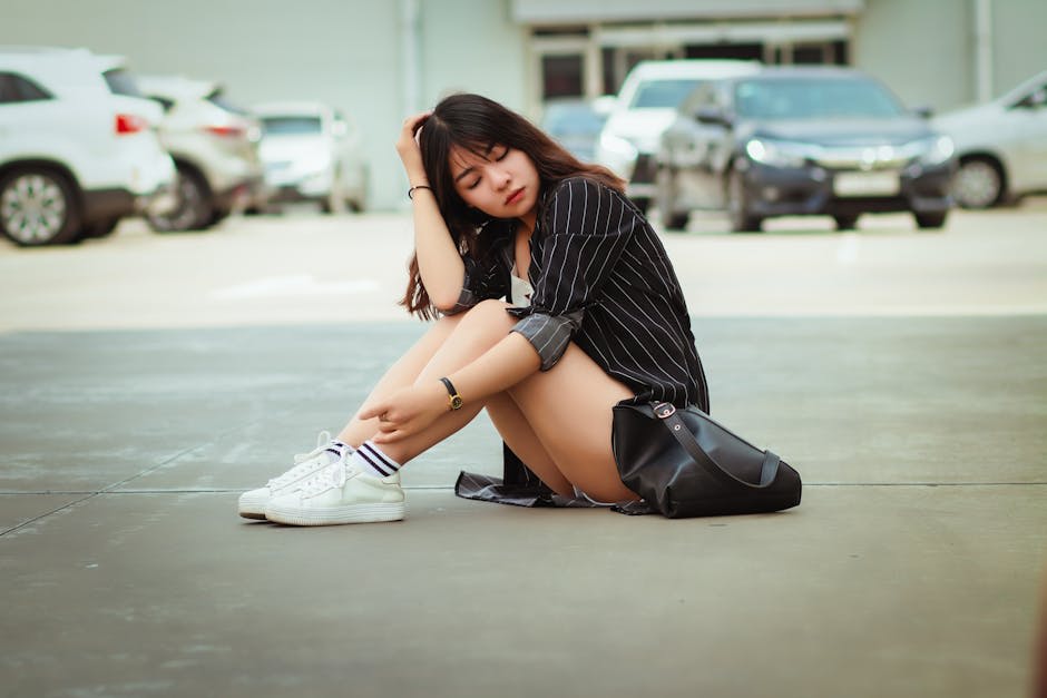 Cách phối thời trang nữ xuân hè đẹp - Người Phụ Nữ Mặc áo Sơ Mi đen Trắng Và Quần đùi Màu Xám Ngồi Trên Bãi đậu Xe