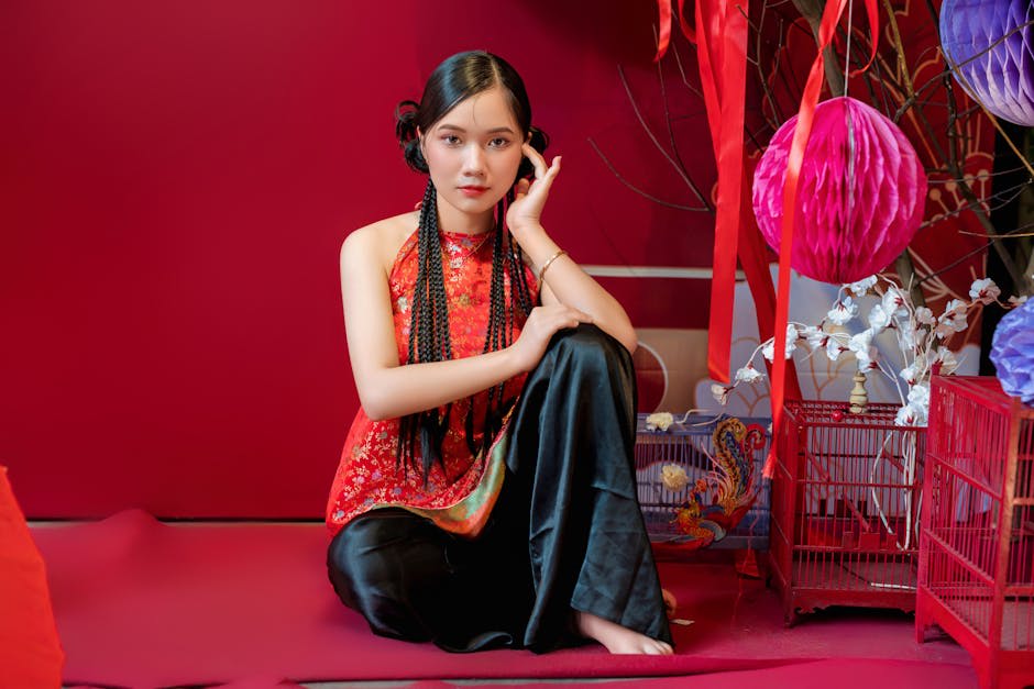 Top kiểu thời trang nữ xuân hè hot trend 2026 - Người phụ nữ trong trang phục truyền thống màu đỏ tạo dáng trên nền lễ h