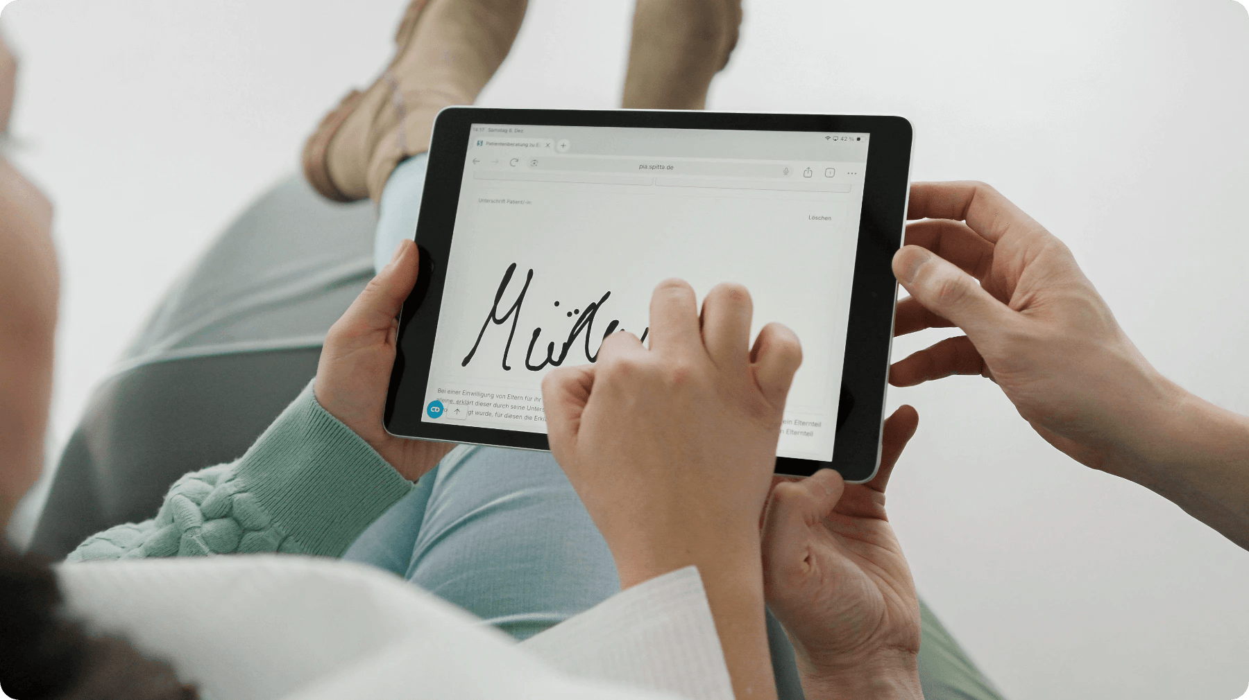 Patientin einer Zahnarztpraxis unterschreibt das Aufklärungsformular digital am Tablet