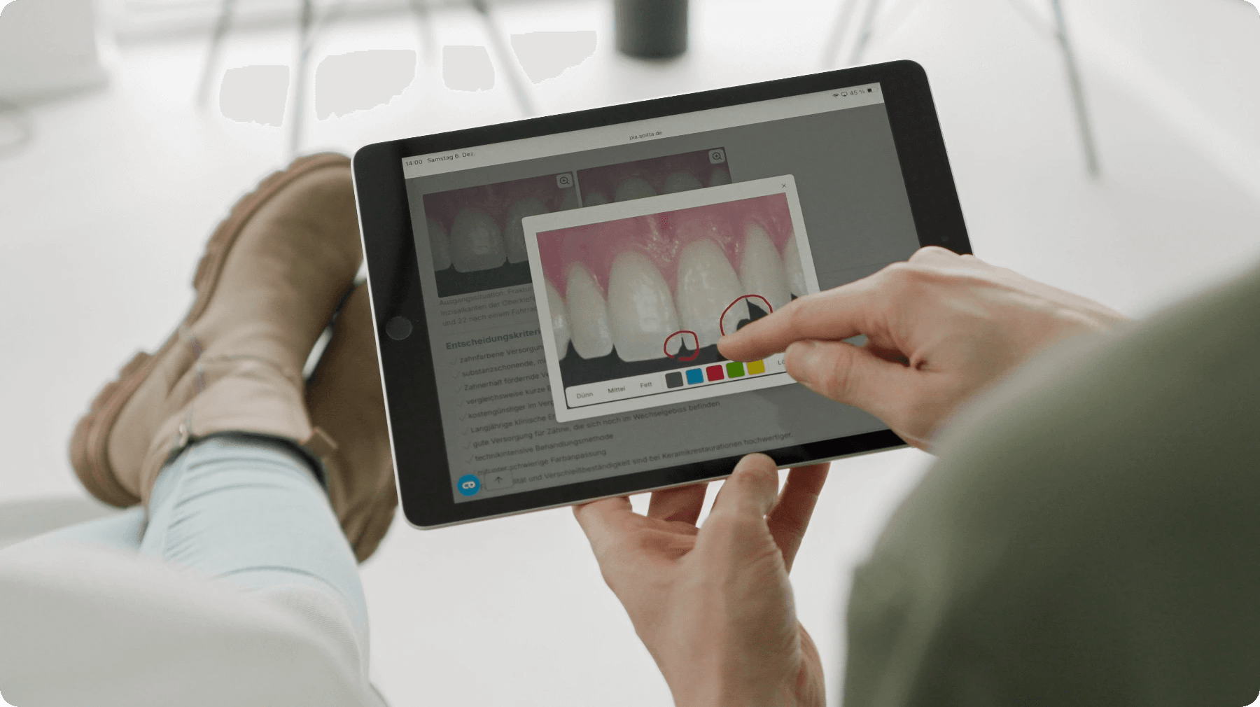 Zahnarzt zeichnet in Behandlungsgrafik am Tablet eine Markierung ein