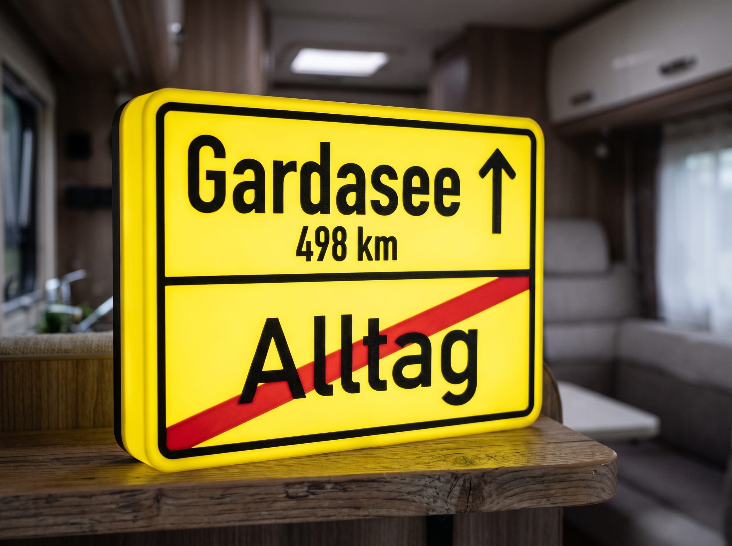 Leuchtende Ortsausgangsschild-Lampe mit Ziel Gardasee und durchgestrichenem Alltag im Wohnmobil