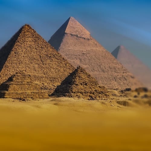 Giza Piramitleri'nin gün batımında çekilmiş etkileyici bir fotoğrafı, Keops, Kefren ve Mikerinos piramitlerini göstermektedir.