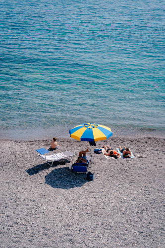 An image of a travel engaged in reading in a beach with a calm atmosphere.