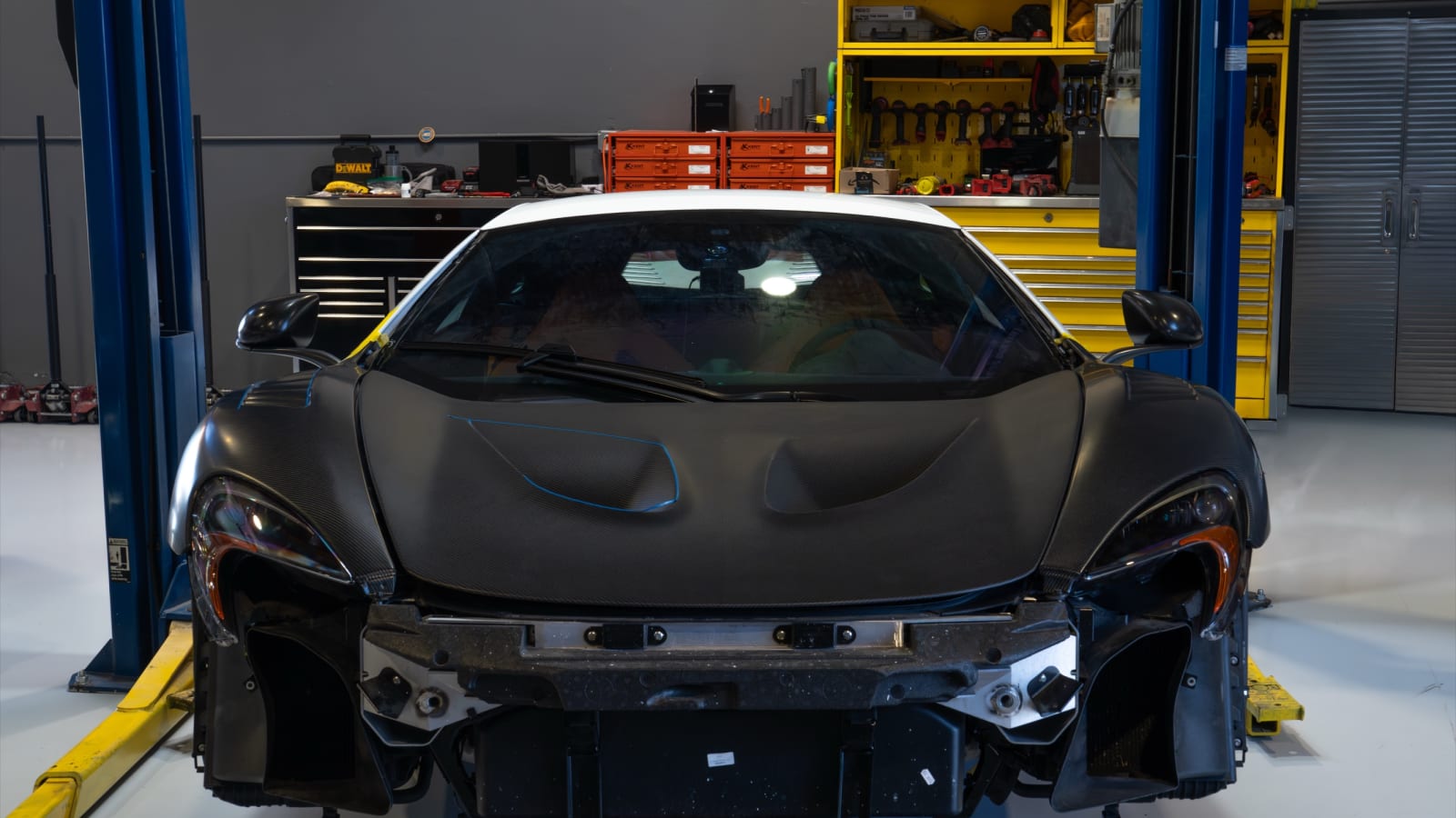 Stripped McLaren body structure on a lift at Pristine Collision Center