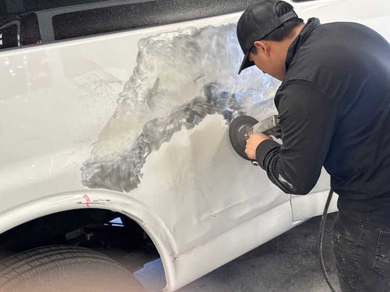Technician sanding body panel