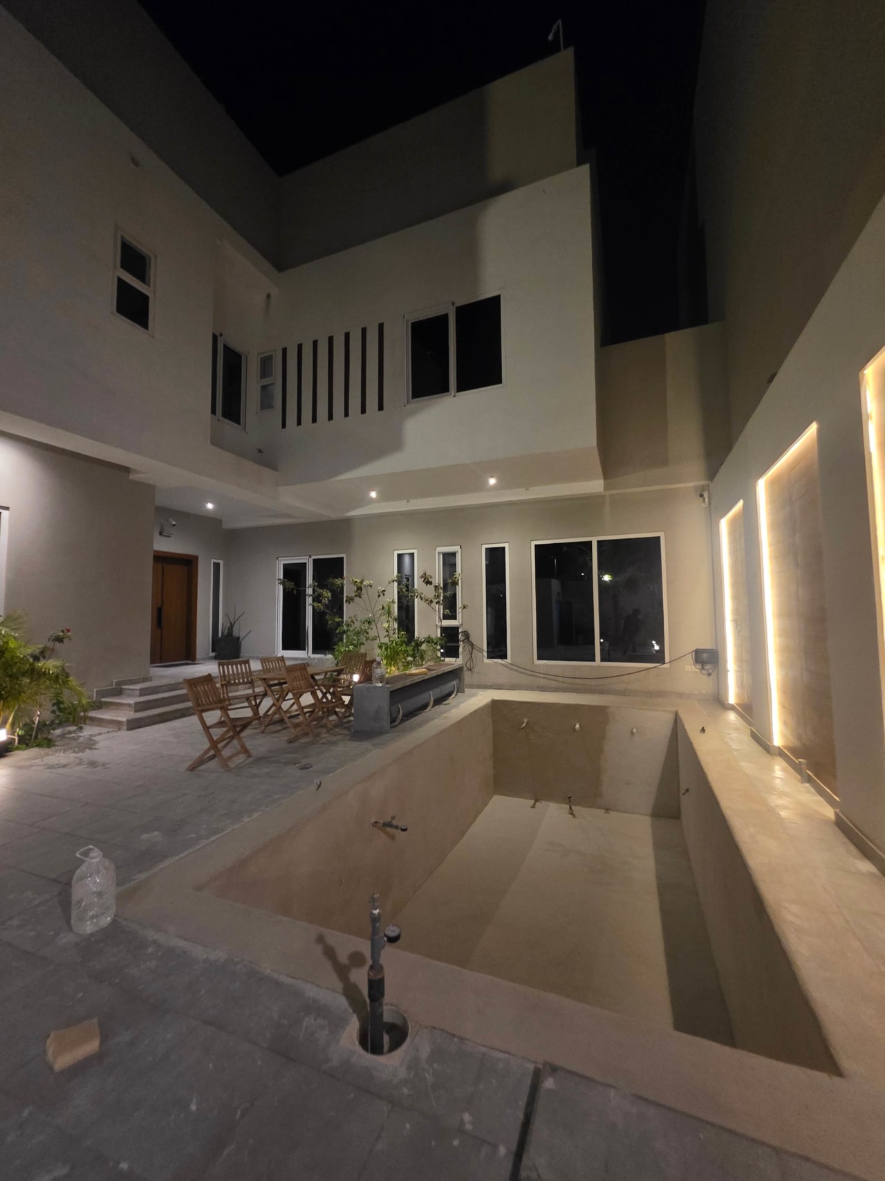 Completed seamless pool at the centre of a two-storey villa courtyard with outdoor seating at night, Obhur Jeddah