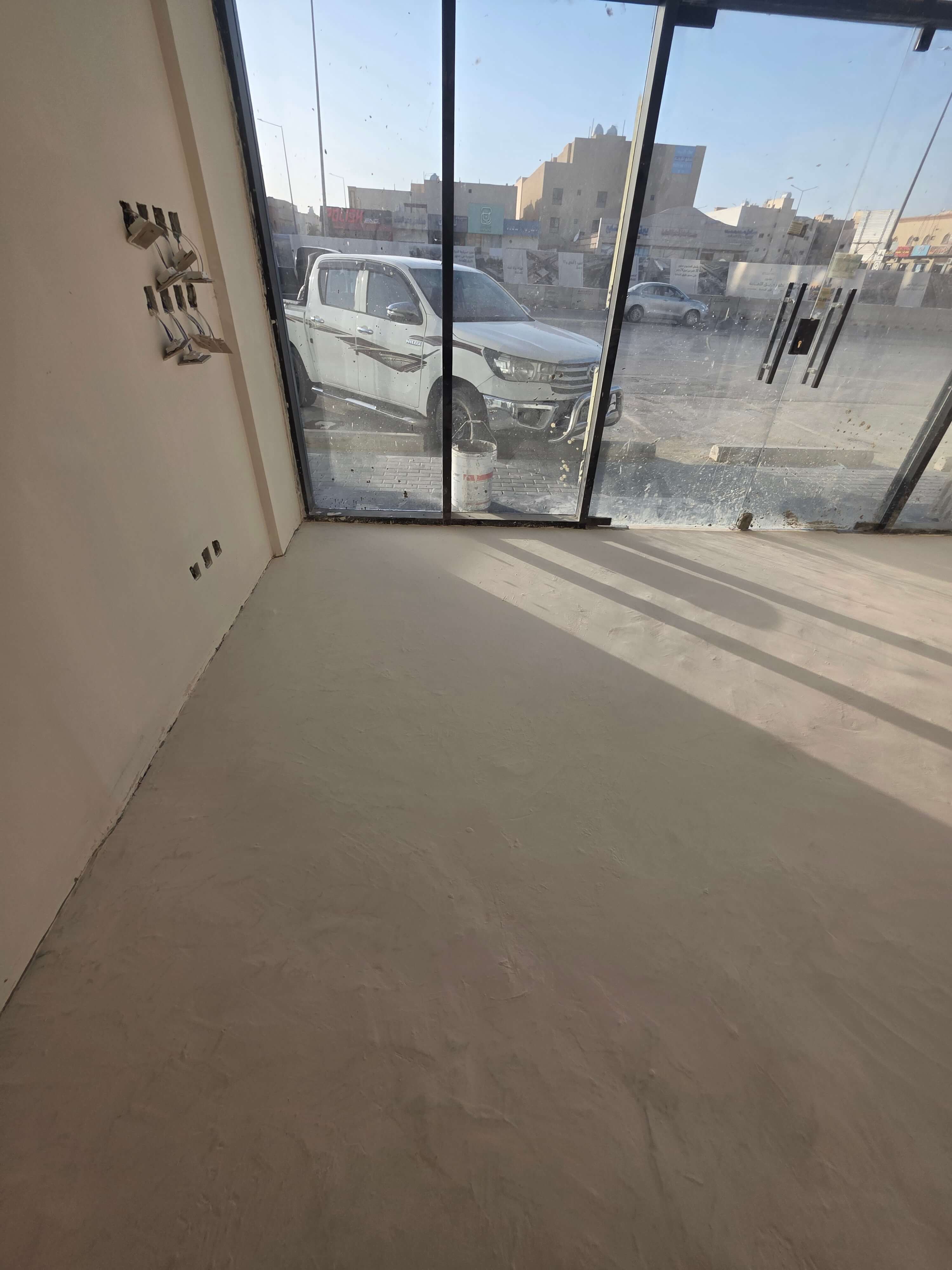بعد — ارضية مايكروسمنت لصالة عرض بواجهة زجاجية — حي الملقا، الرياض