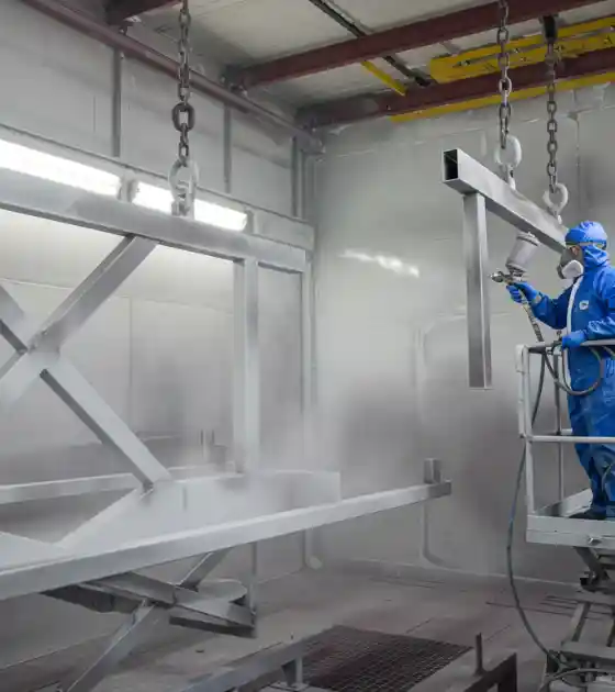 Caldeiraria Santa Rosa - Operador realizando serviço de jateamento industrial em uma estrutura metálica.