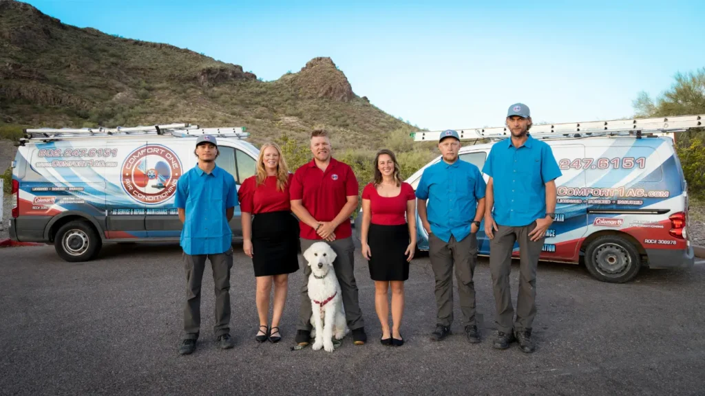 The Comfort One Air Conditioning team standing with their service vans in the Arizona desert