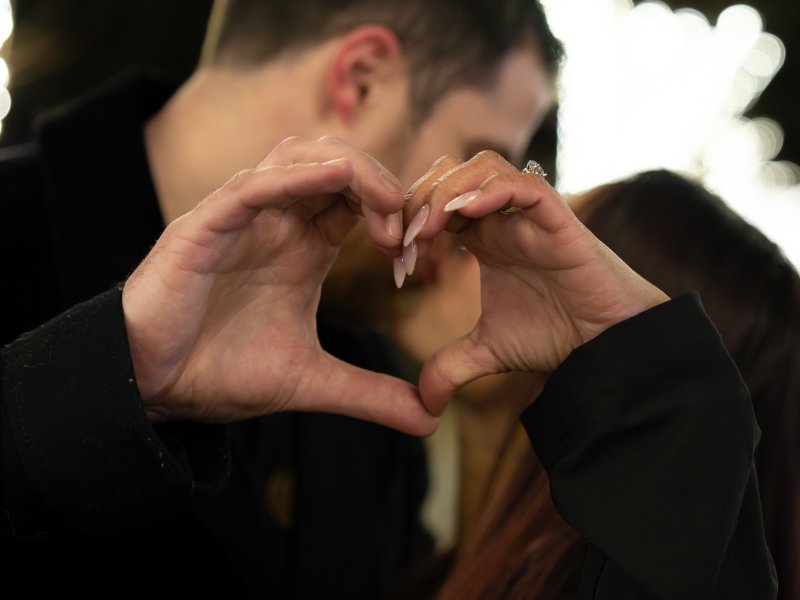 Newly engaged couple walking hand in hand under canopy of trees along Commonwealth Avenue Mall in Boston's Back Bay neighborhood