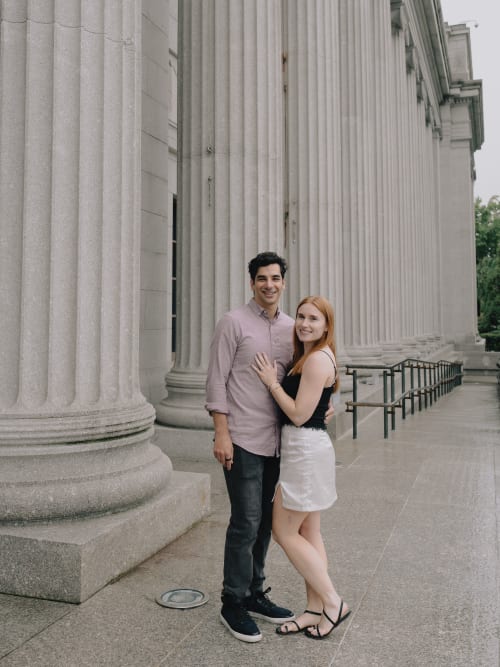 Black-and-white wide portrait of Jared and Abigail in front of the museum's stone facade on a rainy Sunday