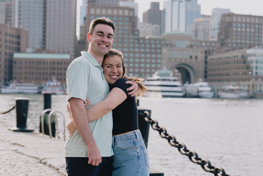 A Fan Pier engagement portrait at blue hour with the Boston Seaport skyline lit across the water