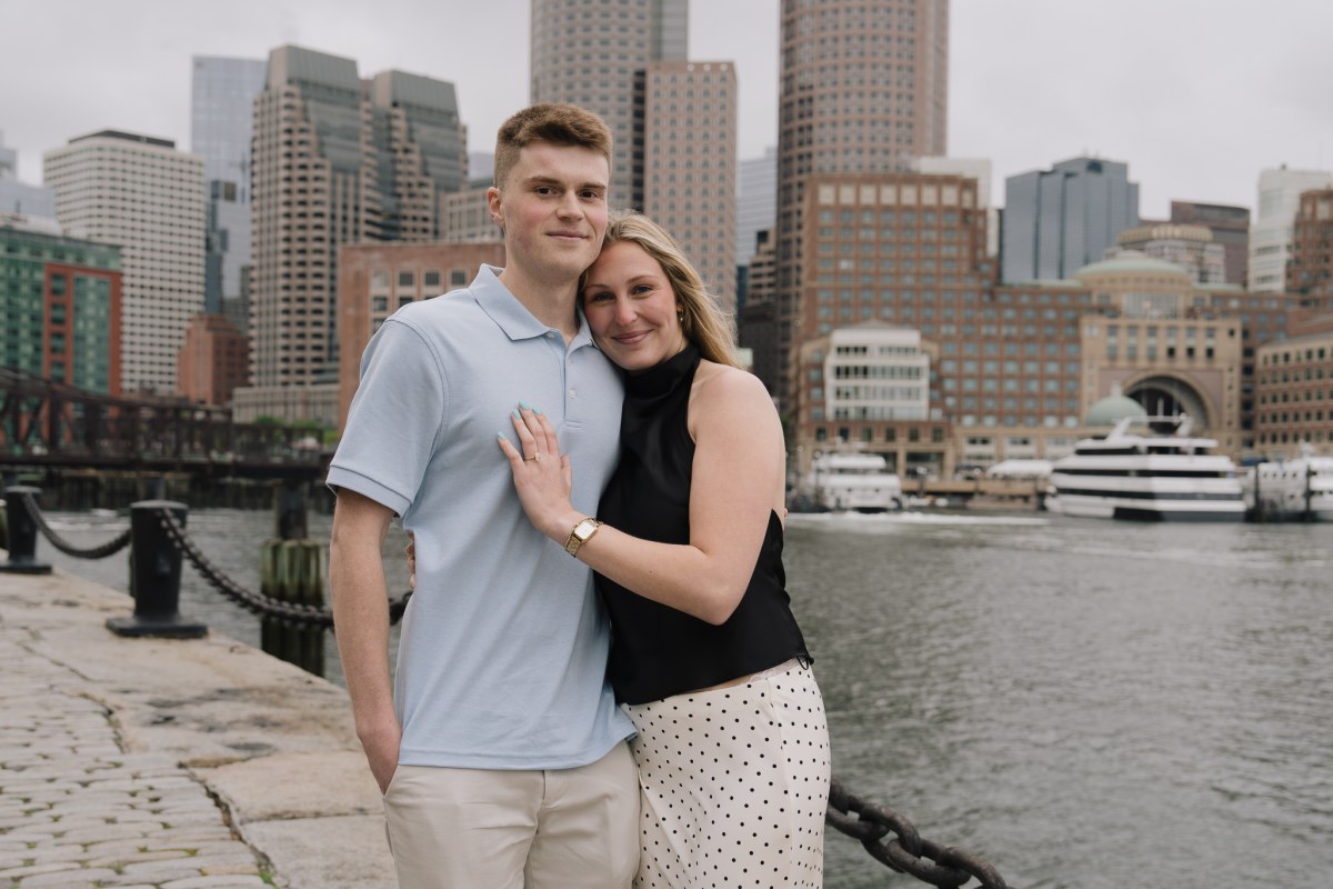 A couple at Fan Pier in the Boston Seaport with the downtown skyline across the channel during golden hour