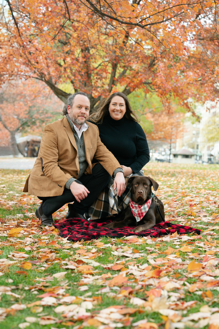Sitting together in the fall leaves with their puppy
