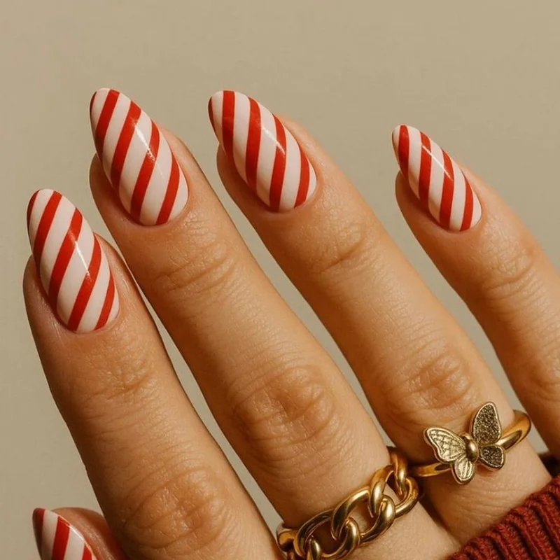 Classic candy cane nails with diagonal red and white stripes for traditional Christmas manicure