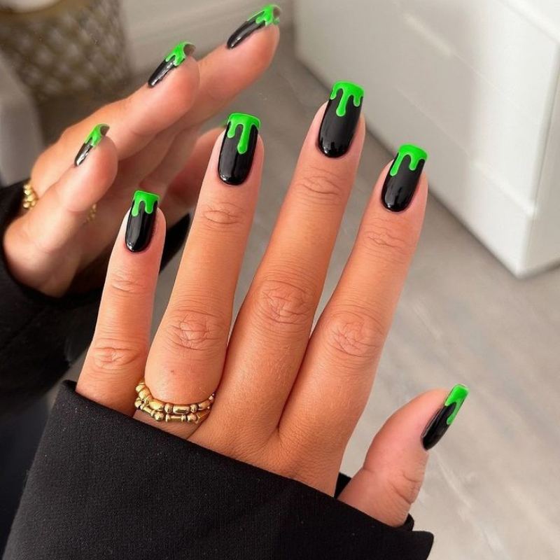 Lime green Frankenstein nails with black stitch marks and bolt details for monster Halloween manicure