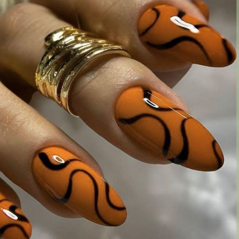 Swirled orange and black marble pattern Halloween nails created with toothpick technique on white base