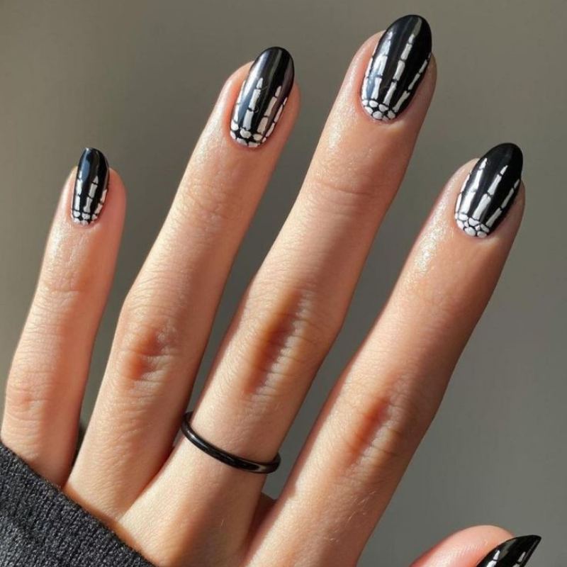 White skeleton bone pattern on black base showing finger bones and joints for spooky Halloween nails