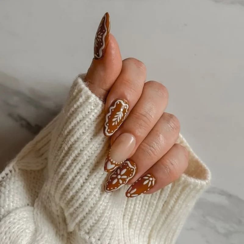 Decorated gingerbread man nail art with intricate white icing patterns and colorful candy details