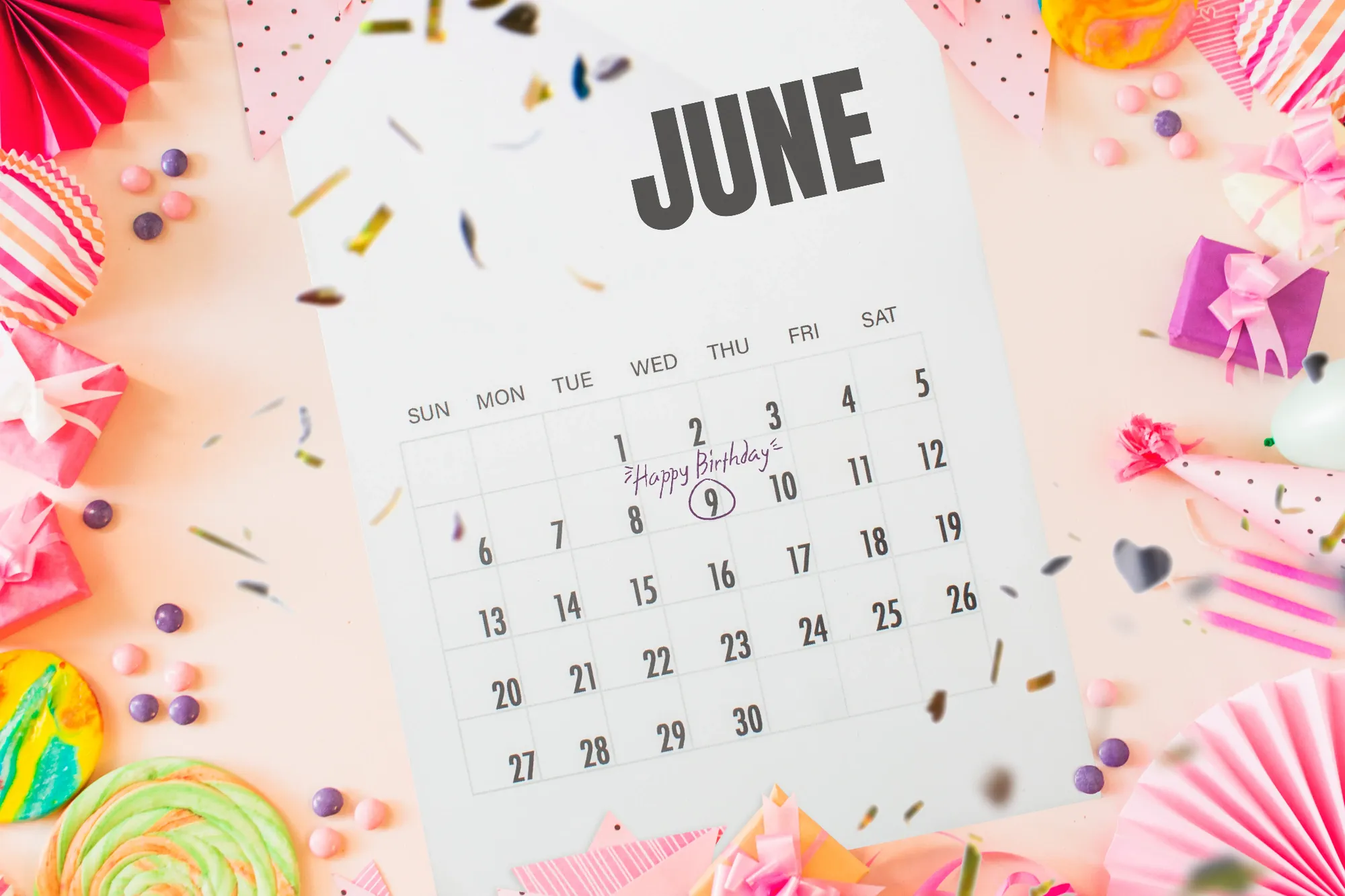 A wall calendar for June with “Happy Birthday” written on the 9th, framed by party hats, gifts and confetti
