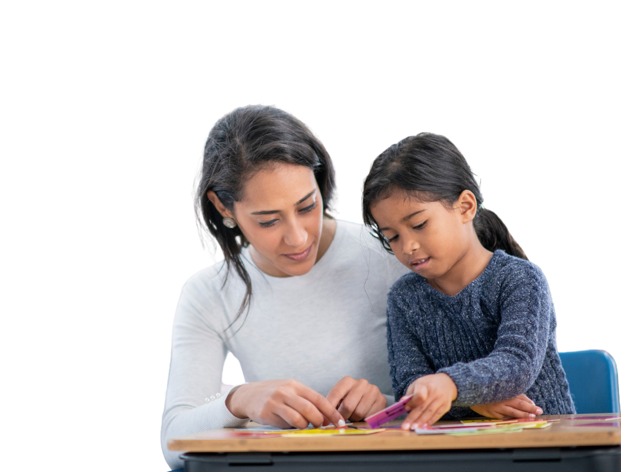 Teaching assistant teaching child at desk