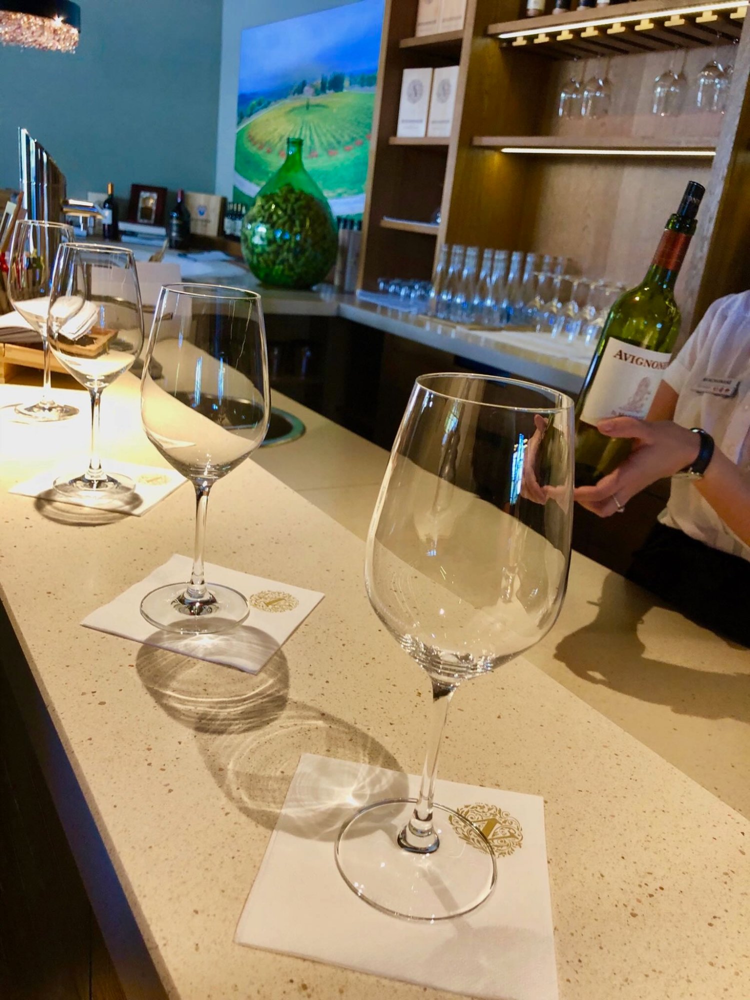 Avignonesi tasting bar — glasses set on branded coasters, sommelier with Avignonesi bottle