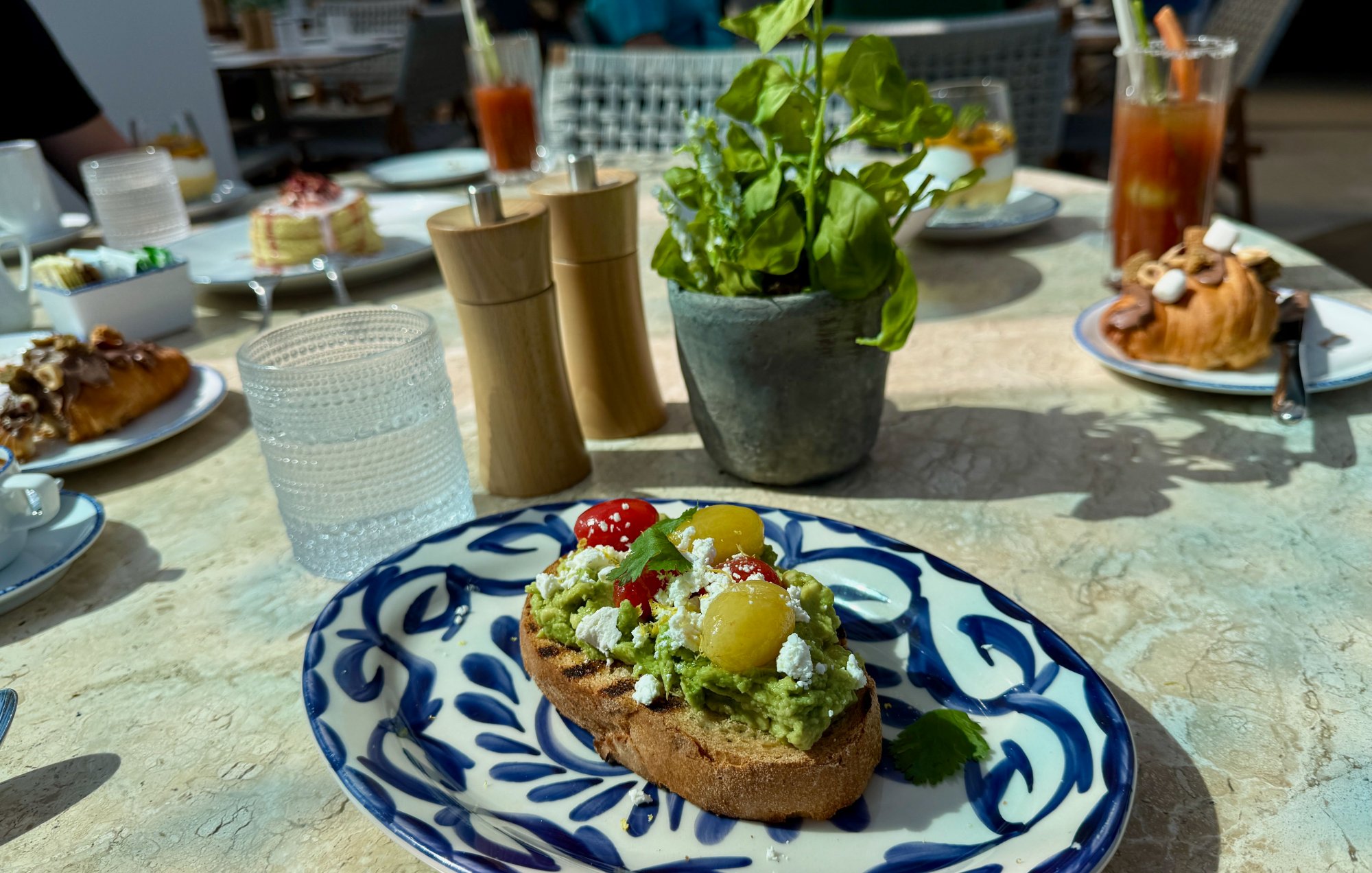 Bora avocado toast with heirloom tomatoes on blue and white plate