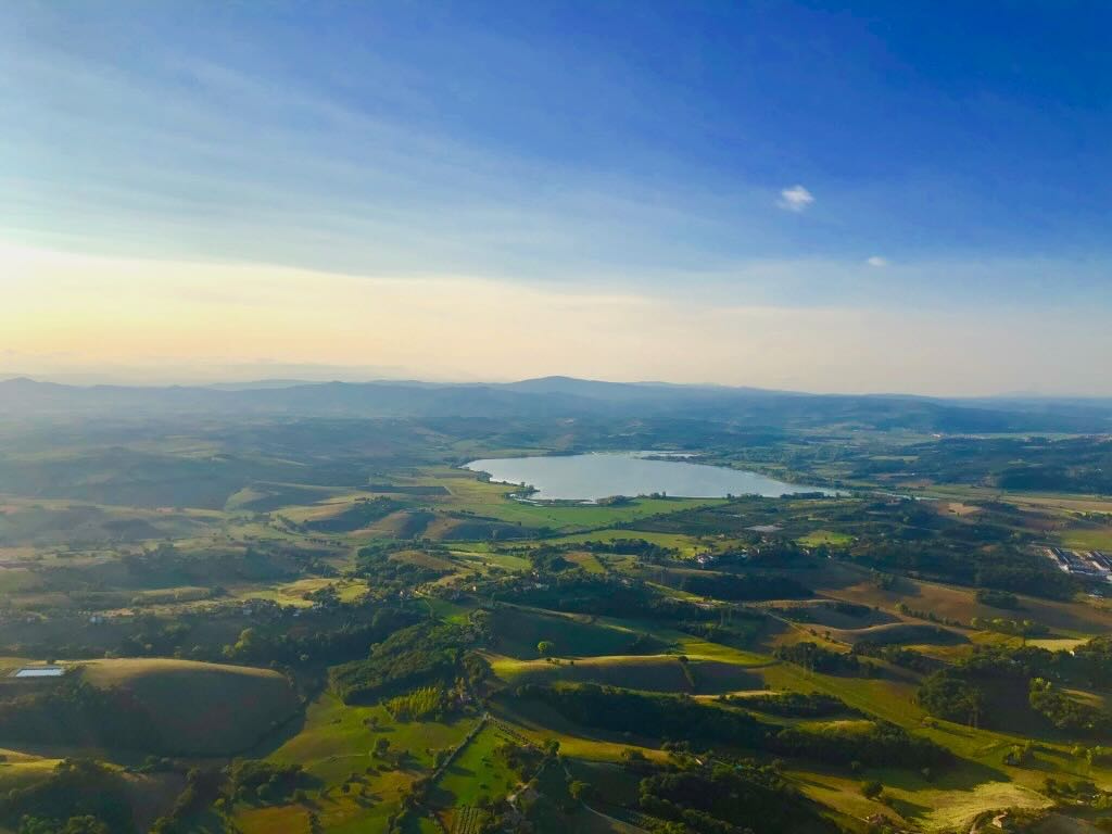 Aerial view of Tuscan lake and rolling hills at sunrise
