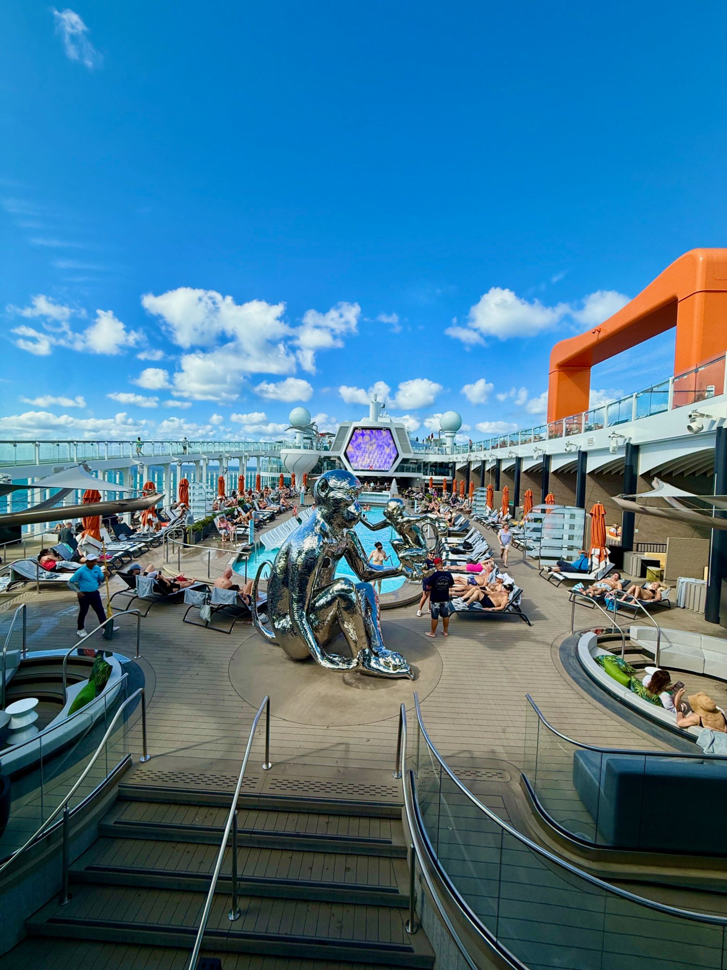 Celebrity Xcel pool deck — chrome sculpture, hexagonal screen, blue Caribbean sky