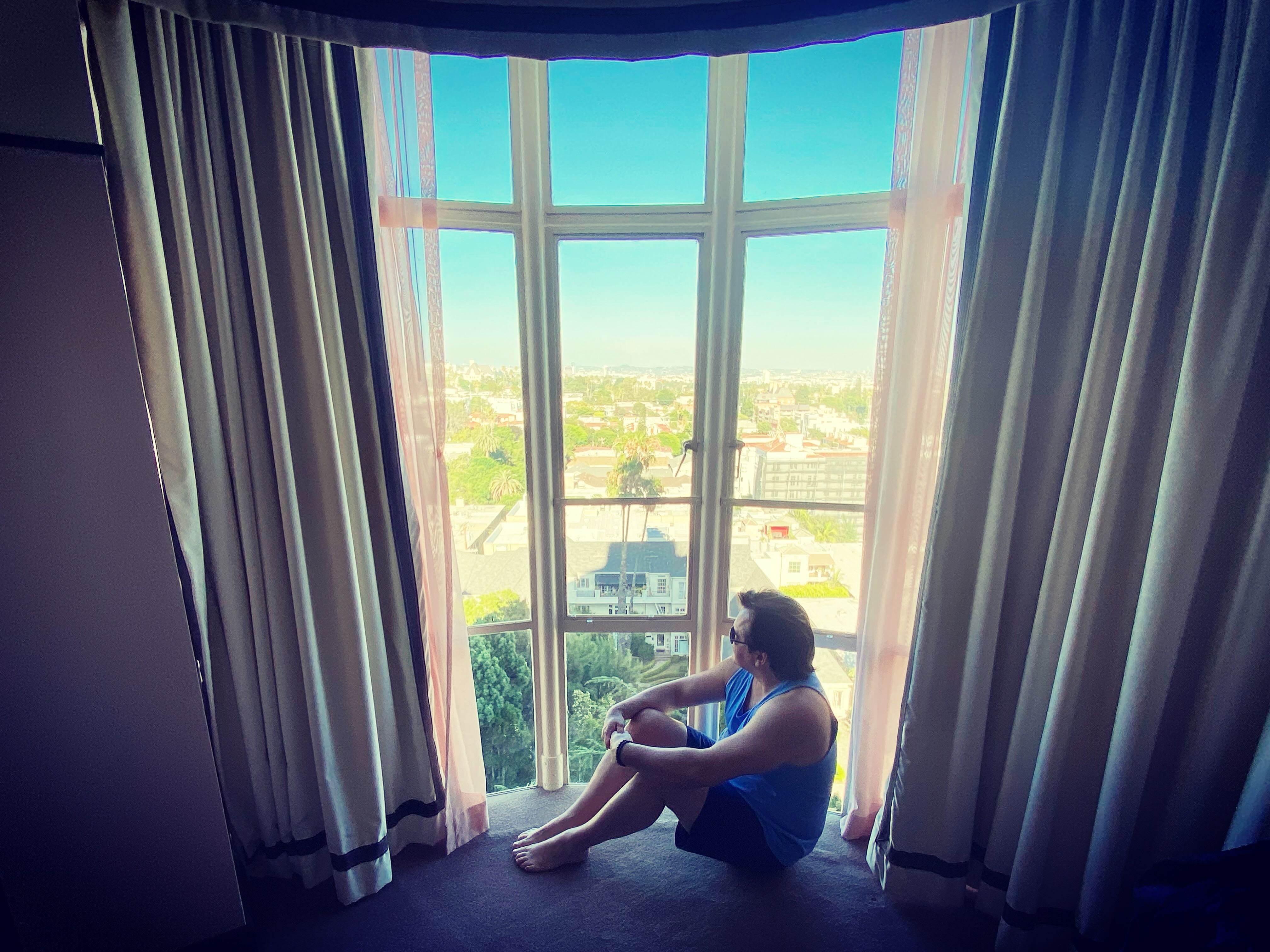 Patrick Raymond at the Deluxe King Suite windows — pondering Hollywood below