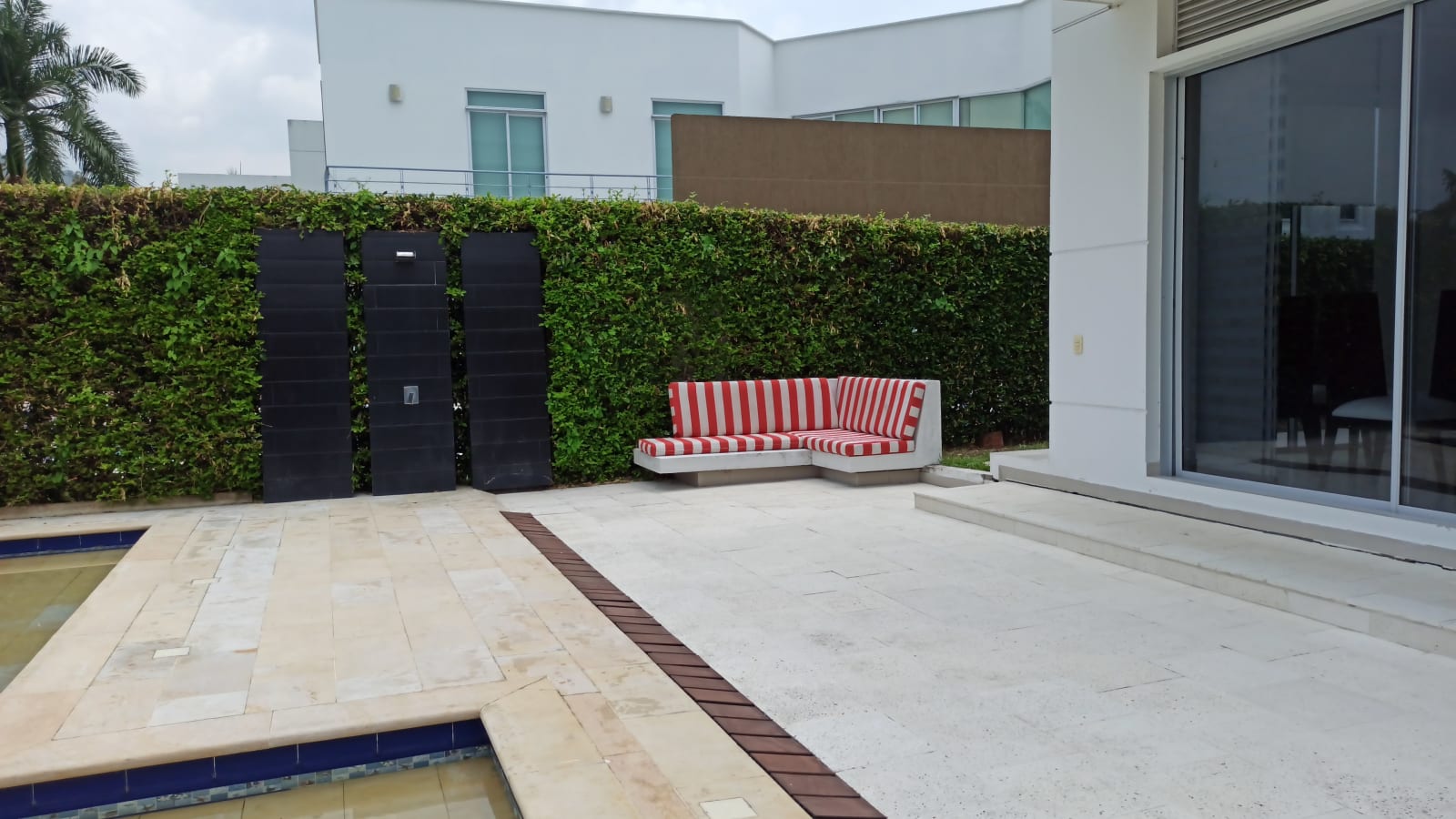 Rincón de descanso en el patio, entre el muro de setos y el piso de piedra.