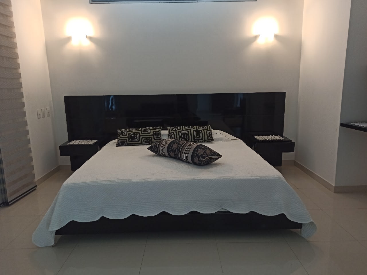 La habitación principal, con cabecero de madera y apliques de luz cálida.