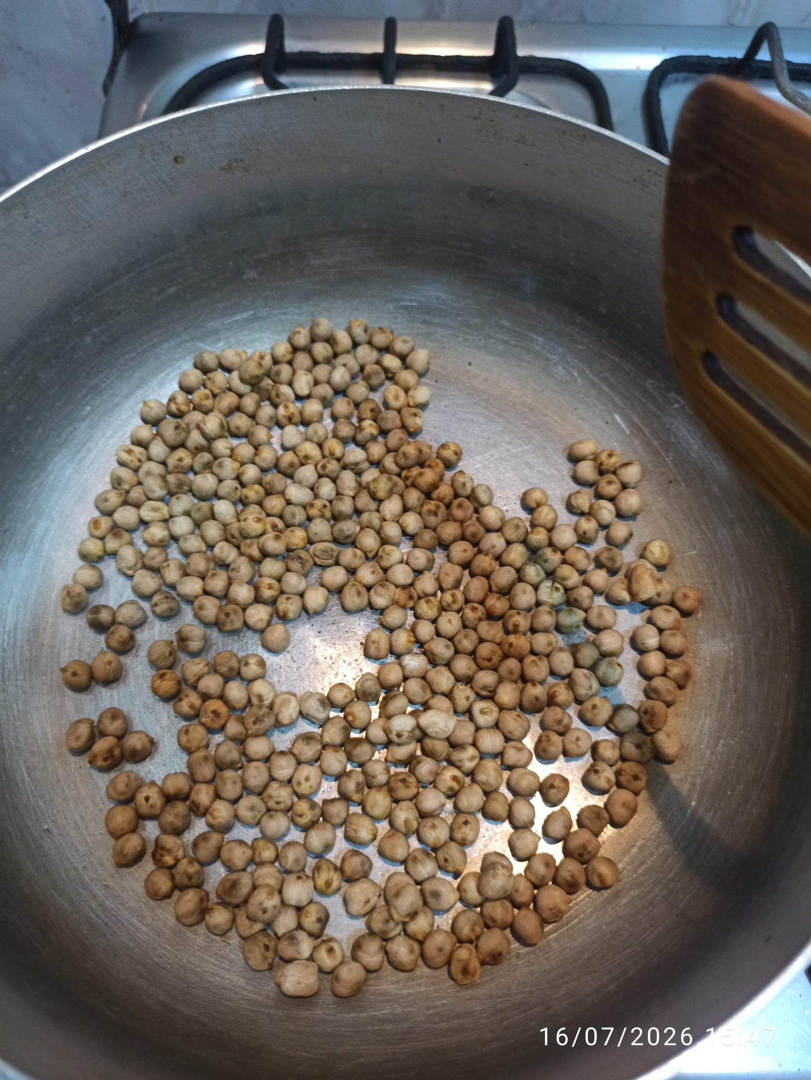 Garbanzos secos tostándose en un sartén de metal sobre la estufa.