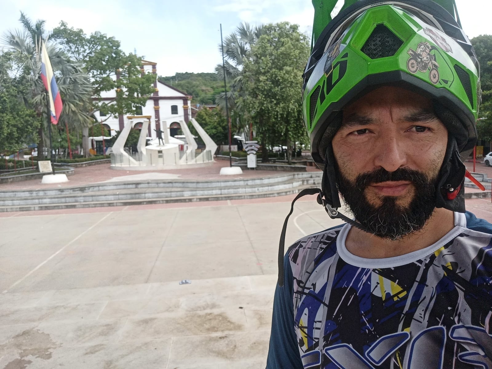 Selfie en la plaza principal de Nilo, Cundinamarca, junto a un monumento, todavía con el casco de moto puesto.