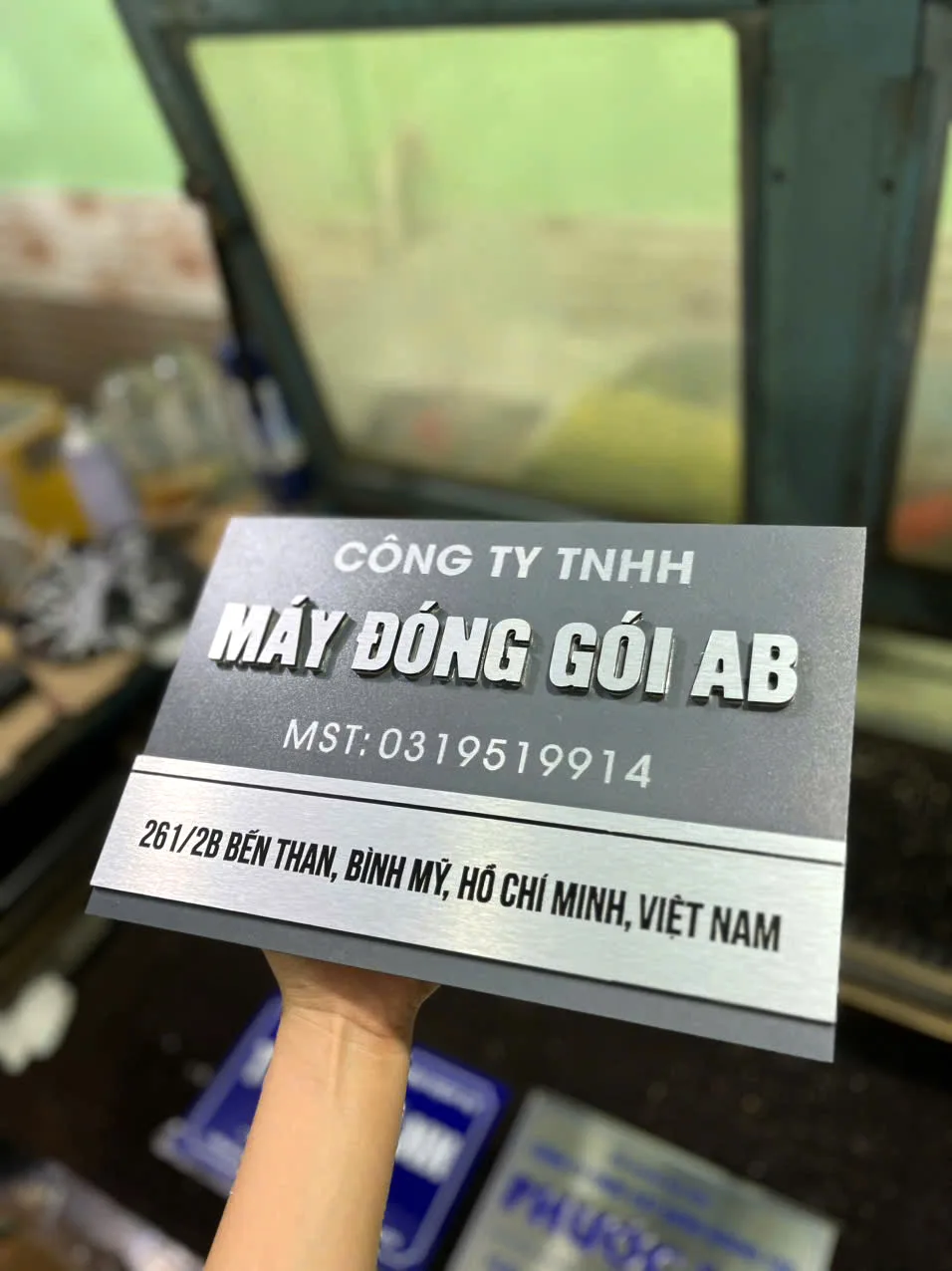 Biển tên công ty chữ nổi bạc nền xám gắn tại sảnh văn phòng