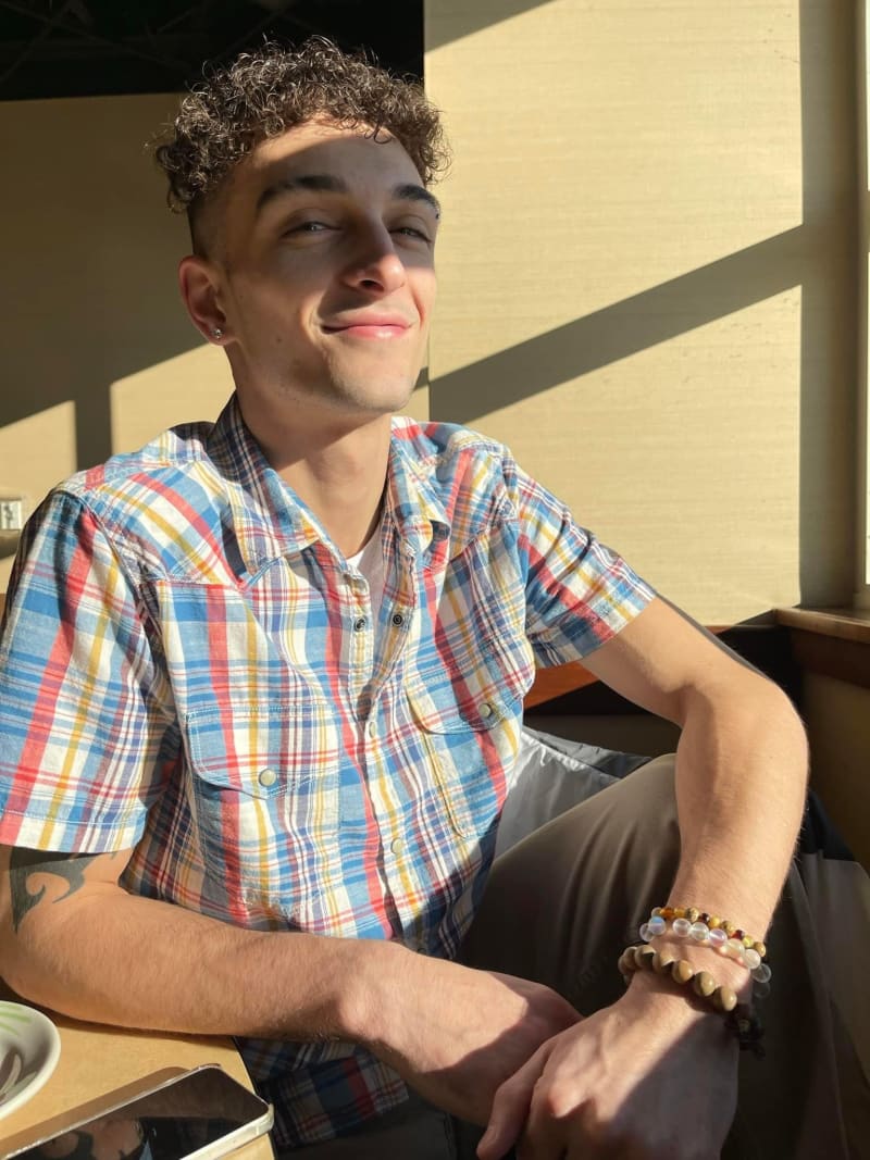 Justin smiling in warm afternoon light wearing a plaid button-up