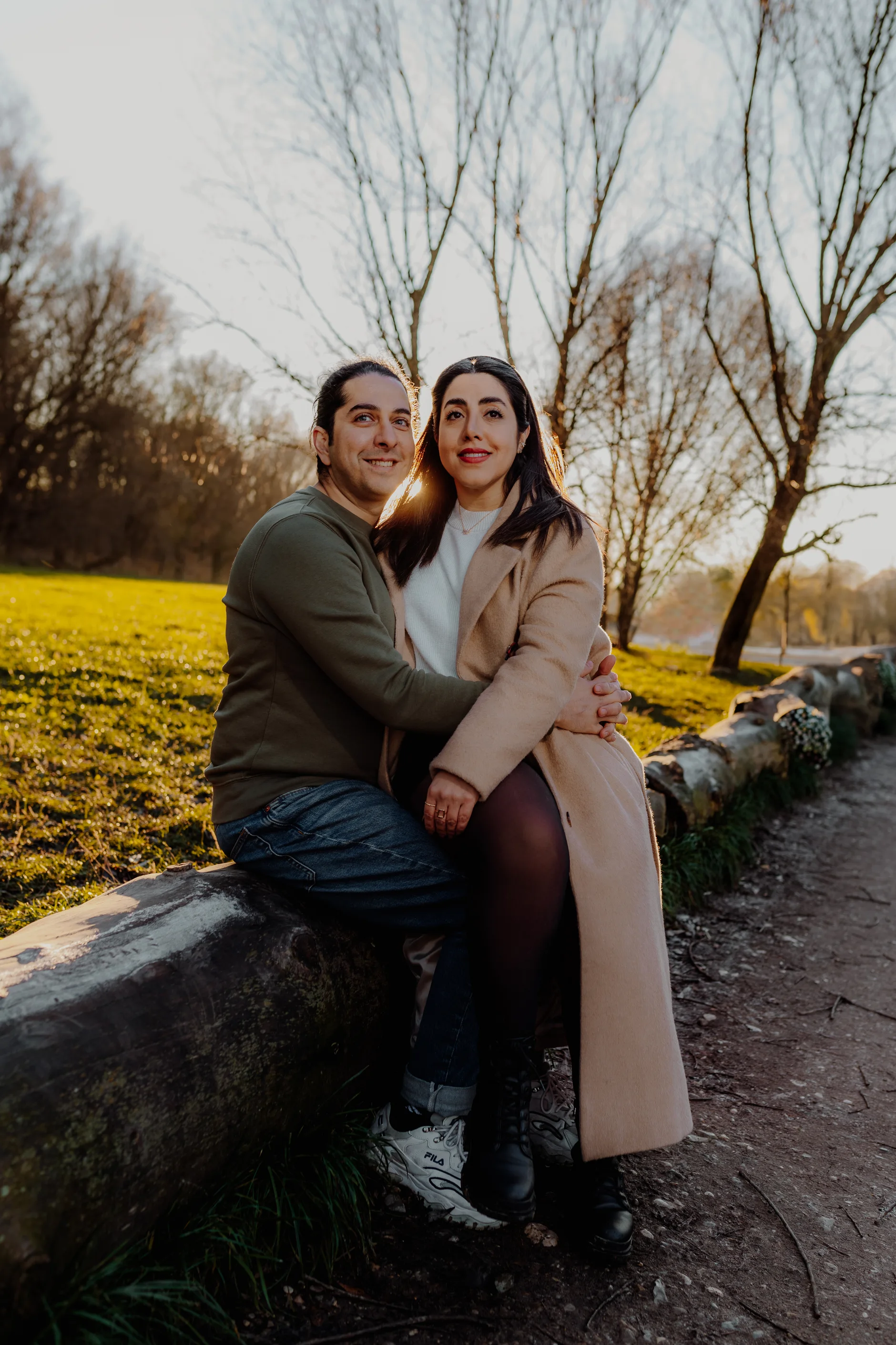 Pareja sentada sobre un muro de piedra bajo el sol del atardecer