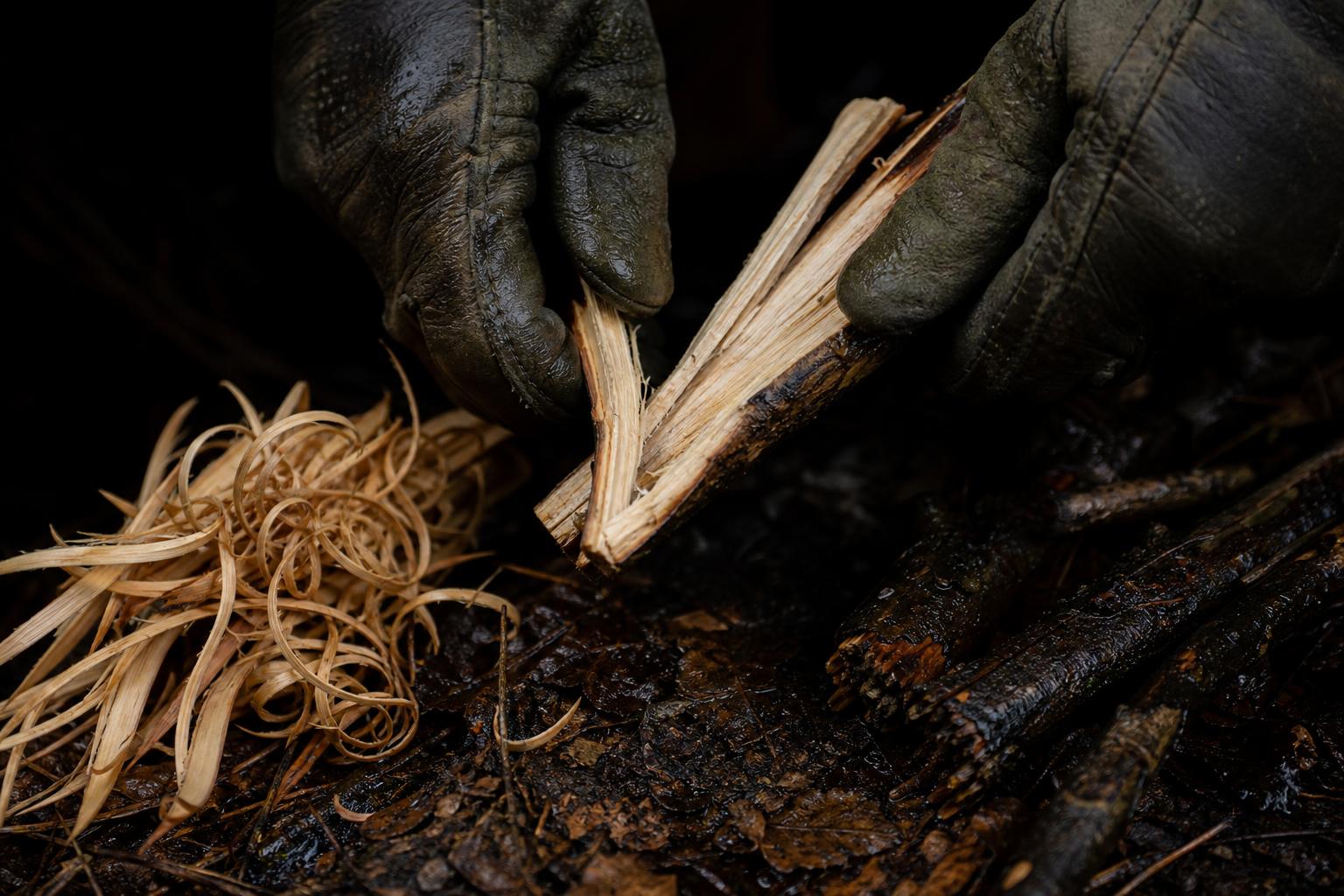 splitting damp wood to expose dry inner kindling for a rain fire