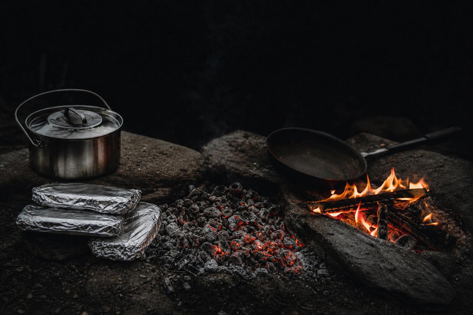 campfire cooking beginner meals in foil packets and steel cookware beside managed coals
