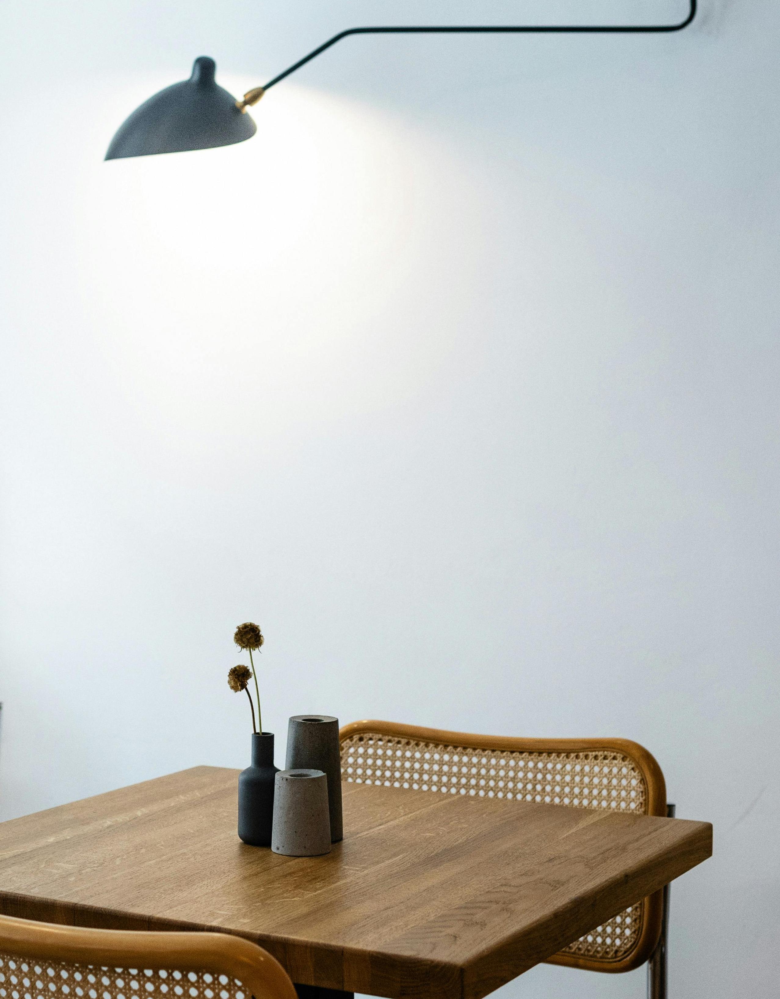 Imagen de fondo donde se ve una lampara y una mesa con dos sillas